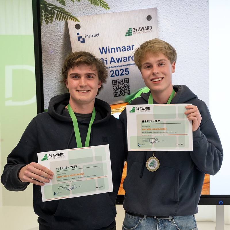 Twee jonge winnaars houden trots hun certificaat omhoog na het winnen van de 3i Award 2025 voor informatica, met medaille en achtergrondbord met logo's.